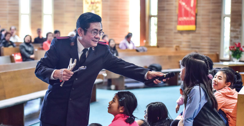 A pastor welcoming children during a Salvation Army New Life Church service